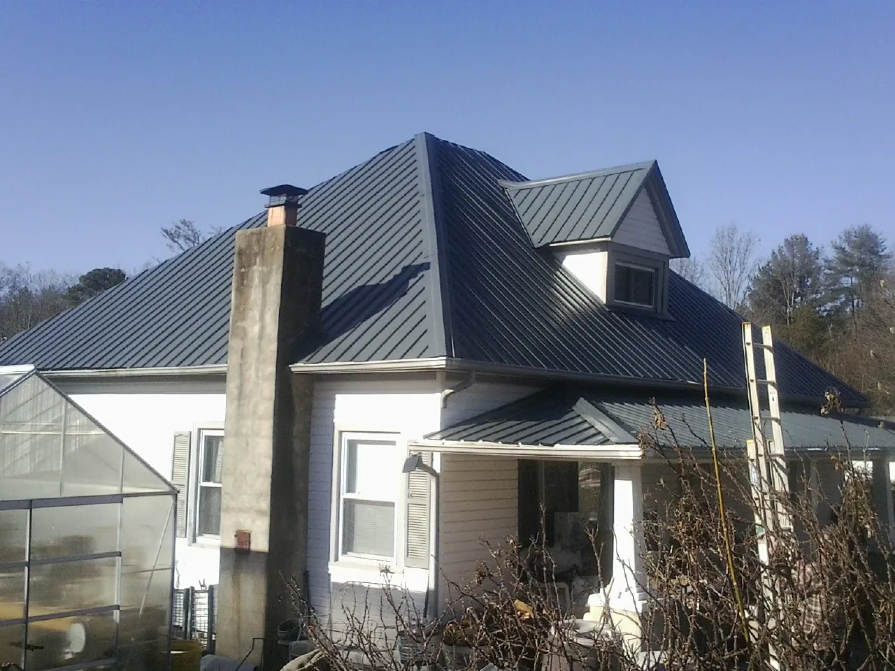 Dark blue standing seam metal roof on a white farmhouse with dormer — Slate & Tile Roof Repair by Roofing Brothers in Walnut Creek