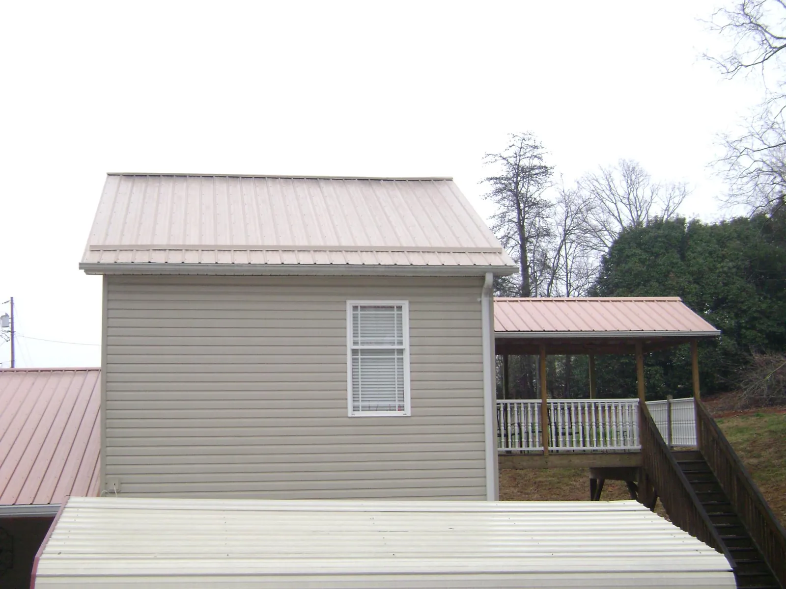 Tan metal roofs on a two story addition and attached porch, from a Roof Replacement job in Walnut Creek